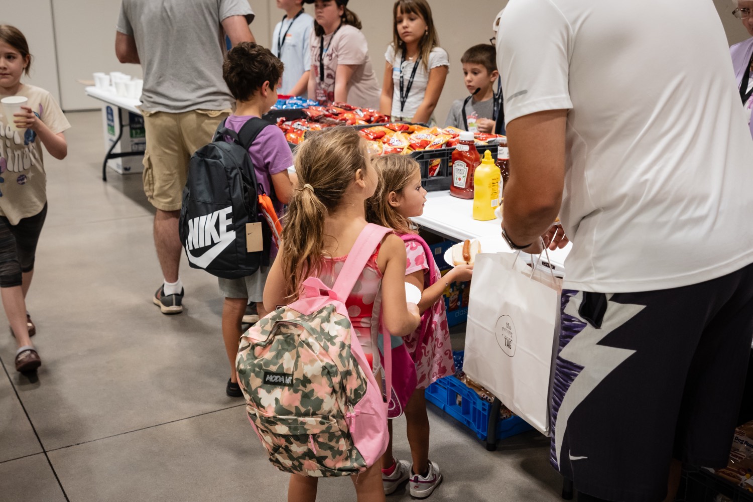 Volunteers handing out backpacks and supplies to children at a give-back