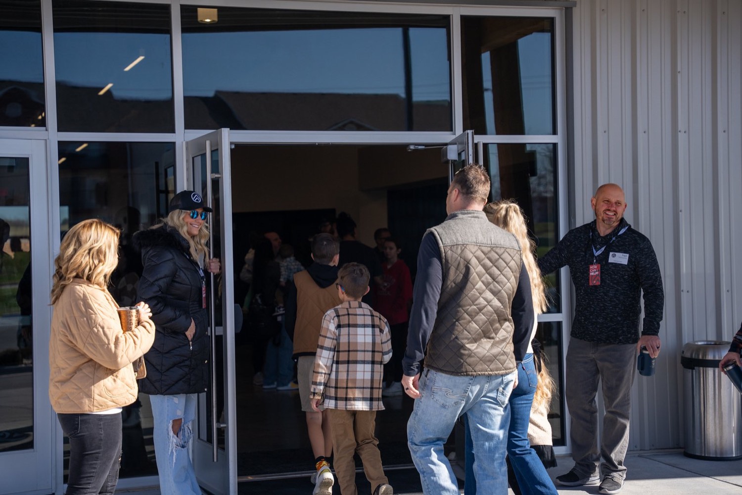 Families walking into the building as a volunteer holds the door open