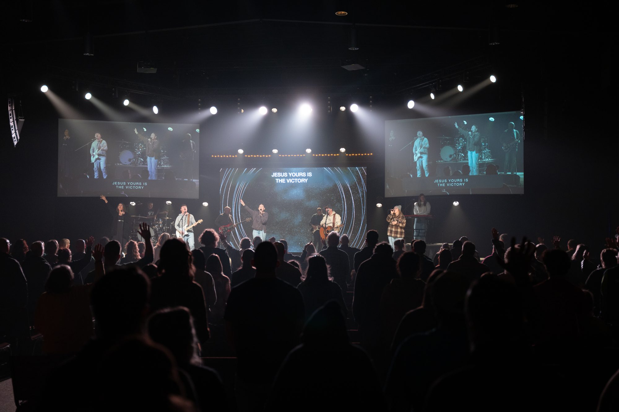 A full auditorium in worship, the band lit on stage under the screens